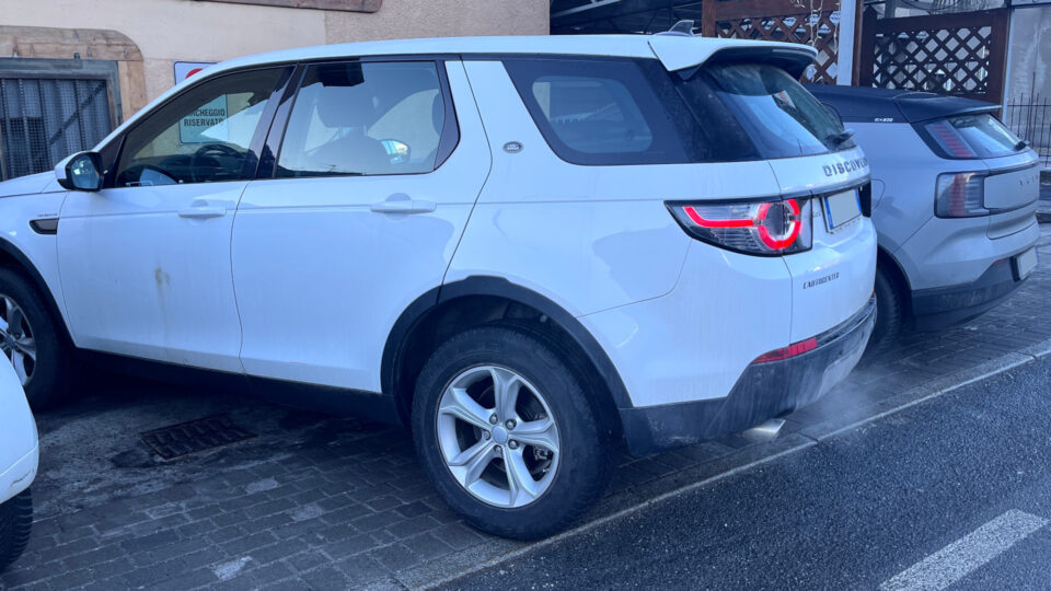 Una Range Rover Discovery lasciata accesa in un parcheggio tra due BEV